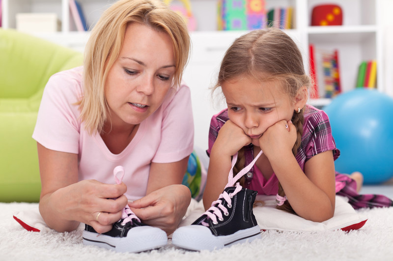Mother helping daughter tie her shoes